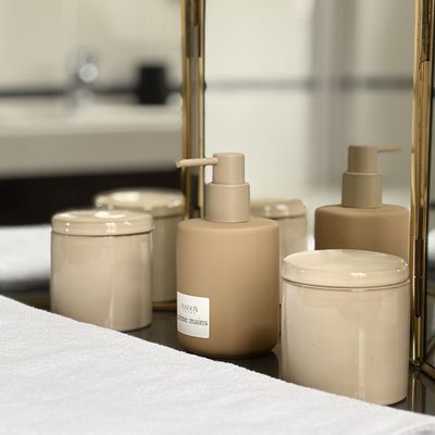 Hand cream and soap bottles in front of a gilded triptych mirror