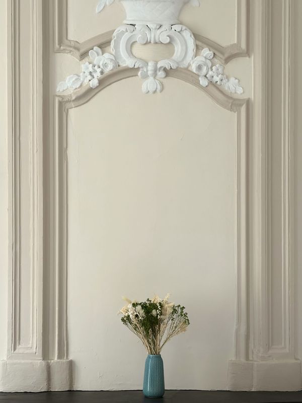 Bouquet of dried flowers in a blue vase in front of stucco mouldings