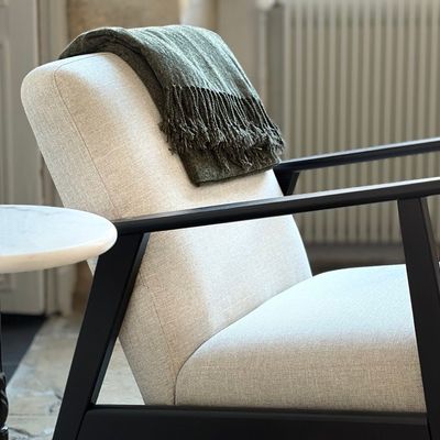 Designer armchair with a linen throw and a round marble table