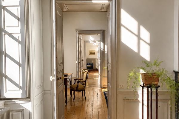 Enfilade perspective of the Suite Côté Jardin: aligned doorways, herringbone parquet and light streaming through